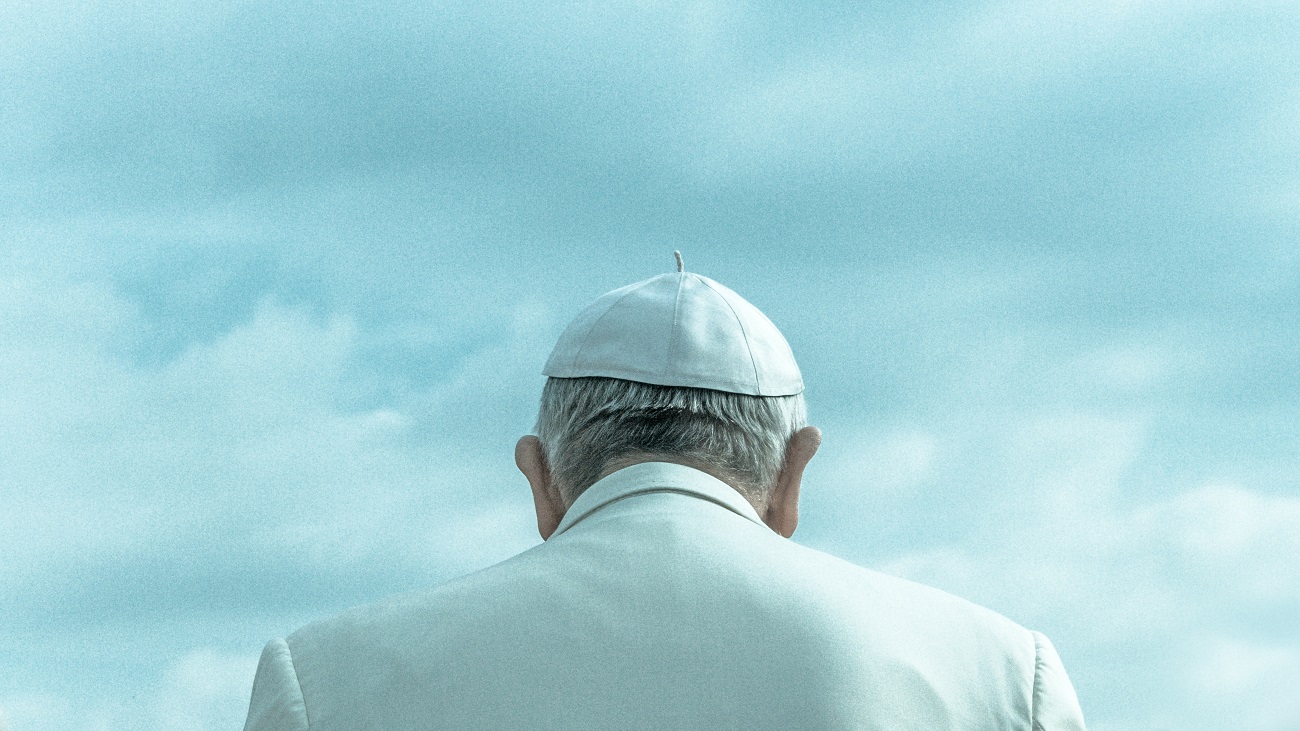 Foto do papa Francisco de costas, um céu azul ao fundo.