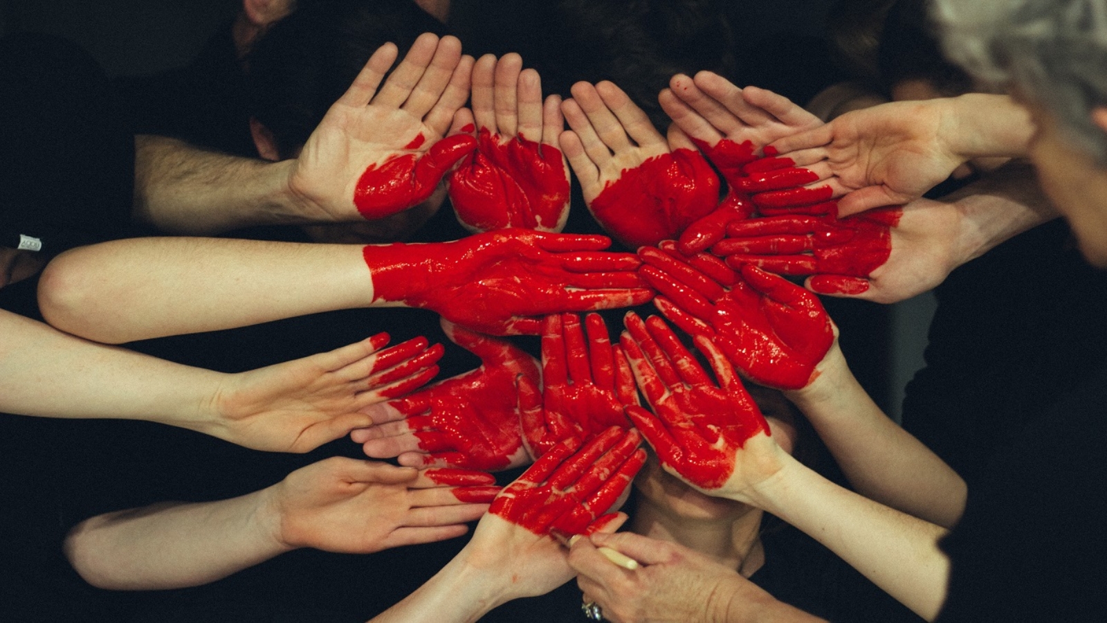 Capa do artigo "ESG humanizado". Foto de várias mãos juntas pintadas de tinta vermelha, em formato de coração.