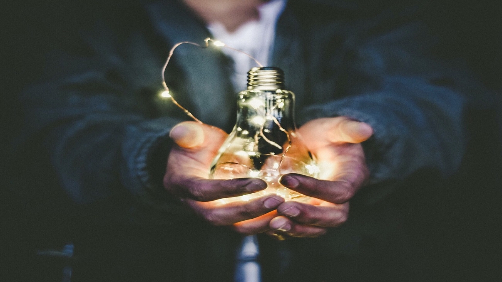 Capa do artigo sobre uso de energia. Foto de um homem segurando uma lâmpada em suas mãos com um fio de luz amarrado em volta dela.